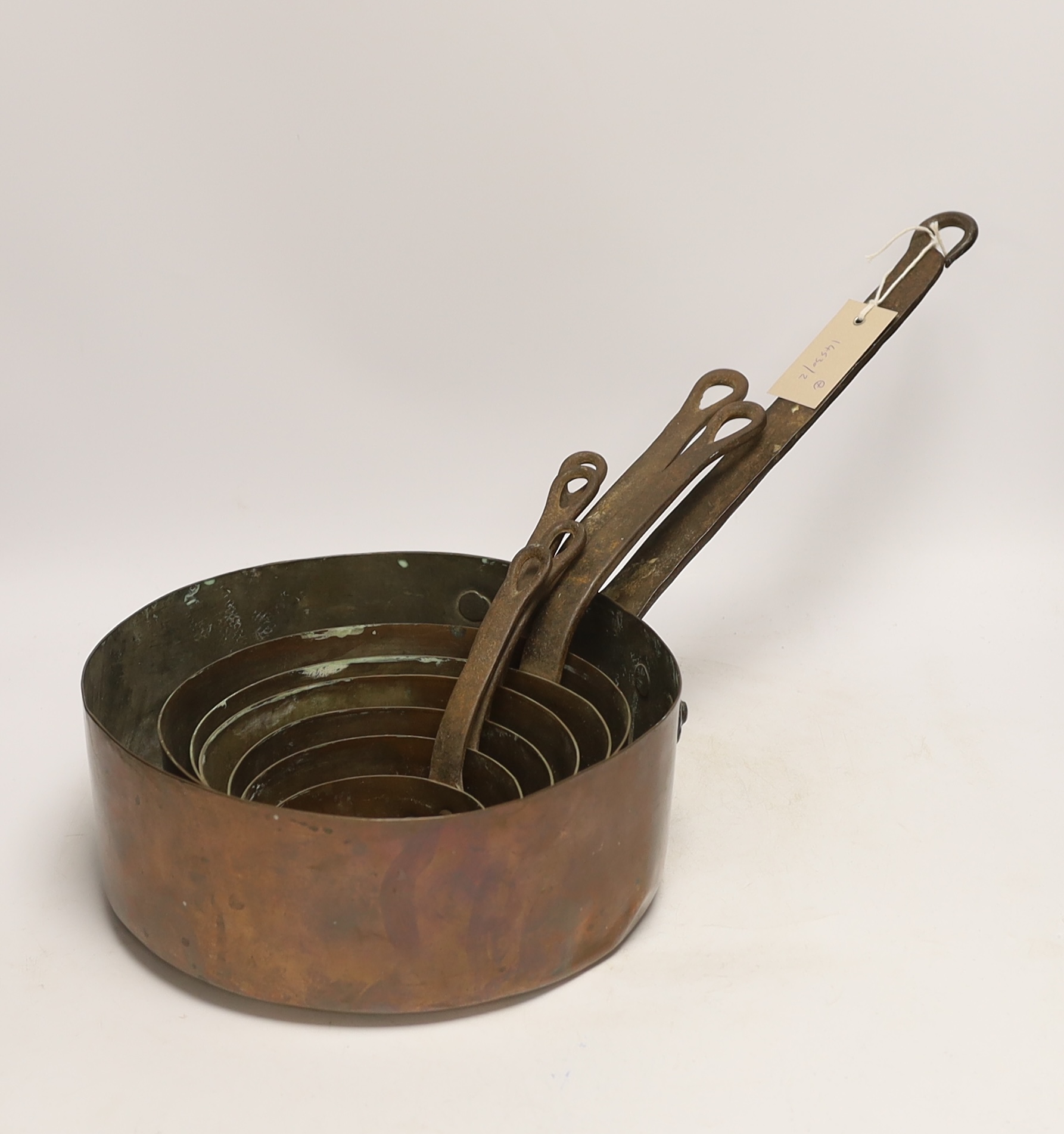Six graduated copper saucepans, largest 27cm diameter